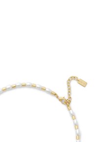 Bracelet en perles blanches et dorées présentant des perles ovales entrecoupées d'éléments métalliques dorés. Fermoir homard et chaîne ajustable.