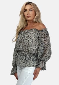 Bluzka typu off-the-shoulder z kwiatowym wzorem w odcieniach niebieskiego i kremowego, z falbanami przy dekolcie i mankietach oraz gumką w talii.