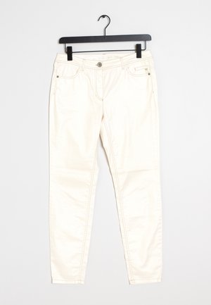 Pantalon slim couleur blanc cassé avec boutons à l’avant, passants de ceinture et poches latérales, suspendu sur un cintre noir sur fond blanc.