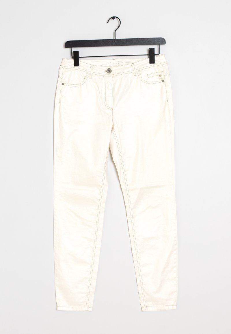 Pantalon slim couleur blanc cassé avec boutons à l’avant, passants de ceinture et poches latérales, suspendu sur un cintre noir sur fond blanc.