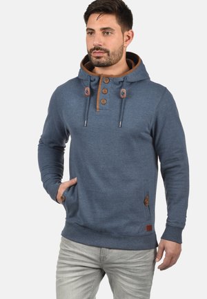 Sudadera azul hecha de tela suave. Cuenta con una capucha con cordón, tres botones de madera y acentos en marrón. Incluye un bolsillo frontal y puños acanalados.