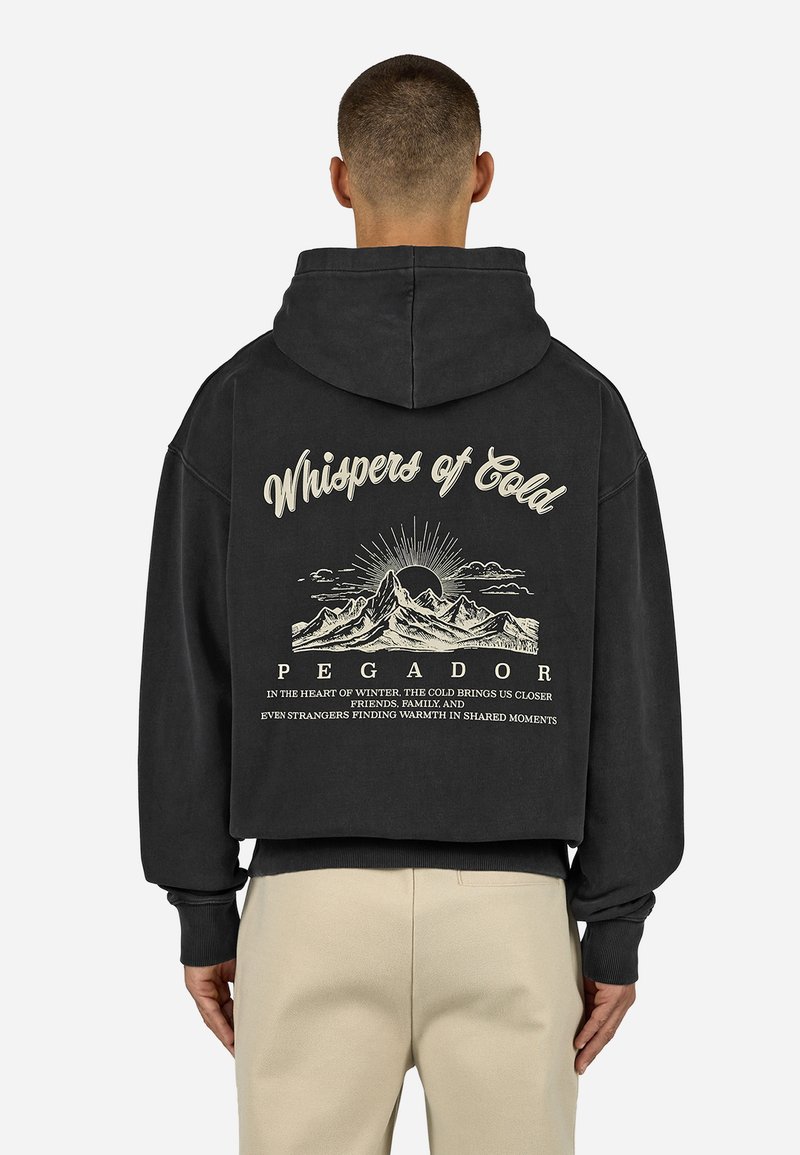 Černá mikina s kapucí, která na zadní straně obsahuje velký grafický design s horami, sluncem a textem. Uvolněný střih s kapucí a žebrovanými manžetami.