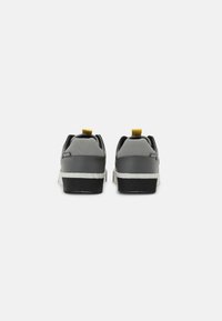 Gray athletic shoes with a smooth texture, featuring a white midsole, black outsole, and a yellow pull tab on the heel.
