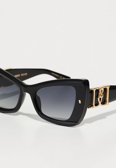 Lunettes de soleil noires avec une monture rectangulaire, des verres dégradés et des éléments en métal doré avec un accent de logo sur la branche.