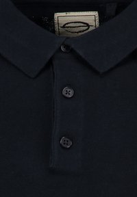 Granatowa koszulka polo z klasycznym kołnierzykiem, trzema ciemnymi guzikami i teksturowanym materiałem z tkanym metkiem w okolicy kołnierzyka.