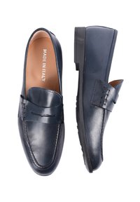 Mocassini in pelle blu navy con una texture liscia, dettagli cuciti e una suola nera bassa e robusta. Internamente presenta l'etichetta "MADE IN ITALY".