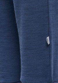 Marinblå tröja med strukturerad stickning. Har en liten tygskylt på sidsömmen. Designen är enkel och åtsittande.