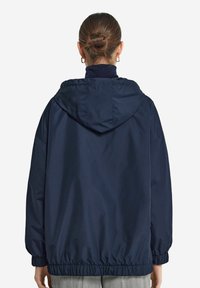 Marinblå hooded jacka med åtsittande midja, elastiska ärmslut och en slät tygkvalitet. Enkelt design, lämplig för avslappnad användning.