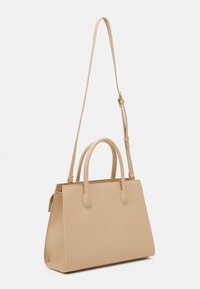 Beżowa torba wykonana z gładkiego syntetycznego materiału. Posiada dwa górne uchwyty, regulowany pasek na ramię oraz sztywny, prostokątny kształt.