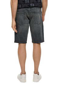 Shorts en denim en noir délavé avec une coupe droite, dotés de deux poches arrière et de coutures contrastantes. Portés avec des baskets blanches.