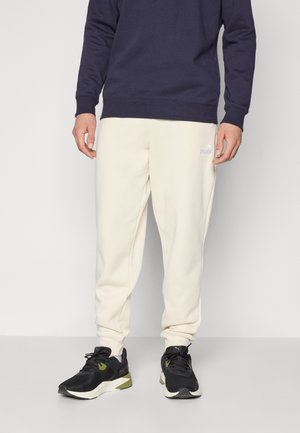 Sweatshirt in navy blue, paired with cream sweatpants. Outfit complemented by black athletic shoes with green accents and a sleek design.
