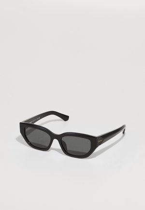 Óculos de sol retangulares pretos com lentes escuras, armações de plástico espessas, frente com bordas angulares e acabamento ligeiramente brilhante. Detalhe em dourado na haste.