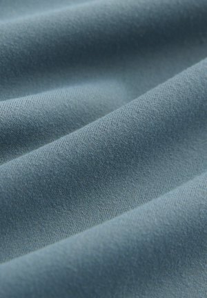 Weiches, strukturiertes Gewebe in einem sanften Blauton mit einer glatten Oberfläche und einem diagonalen Webmuster, das subtile Tiefe und Reichtum zeigt.