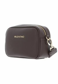 Sac en cuir grainé marron avec ferrures dorées, forme rectangulaire, logo à l'avant et fermeture éclair. Comprend une bandoulière amovible et une surface texturée.