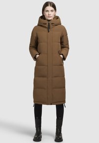 Barna párnázott hosszú kabát kapucnival, elülső cipzárral és oldalsó zsebekkel; az alján húzózsinórok találhatók, és sima szövettextúrával rendelkezik.