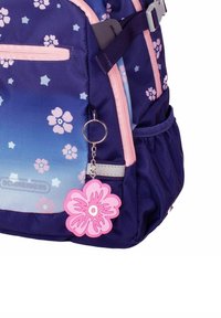 Marineblauer Rucksack mit einem Verlauf in Blautönen, pinkfarbenen Akzenten, floralem Muster und einem pinkfarbenen Blumenanhänger an einer Reißverschlusstasche.