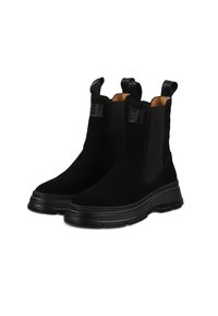 Botas Chelsea de ante negras con paneles laterales elásticos, punteras redondas y suelas de goma texturizada. Incluyen lengüetas para facilitar su puesta.