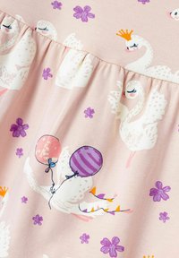 Tessuto rosa chiaro con un design giocoso che presenta cigni bianchi, fiori viola e palloncini illustrati in tonalità di rosa e viola.