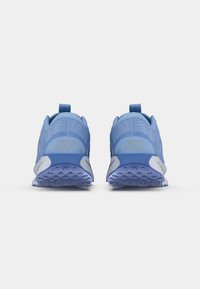 Modri Nike športni copati z teksturiranim mrežastim materialom, zanka za poteg in ukrivljeni beli detajli. Podroben gumijast podplat za oprijem. Zadašnji pogled.