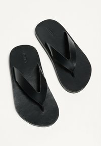 Papuci negri cu o textură netedă și moale. Au o curea largă în formă de V și o talpă plată. Design minimalist, fără embellishments suplimentare.