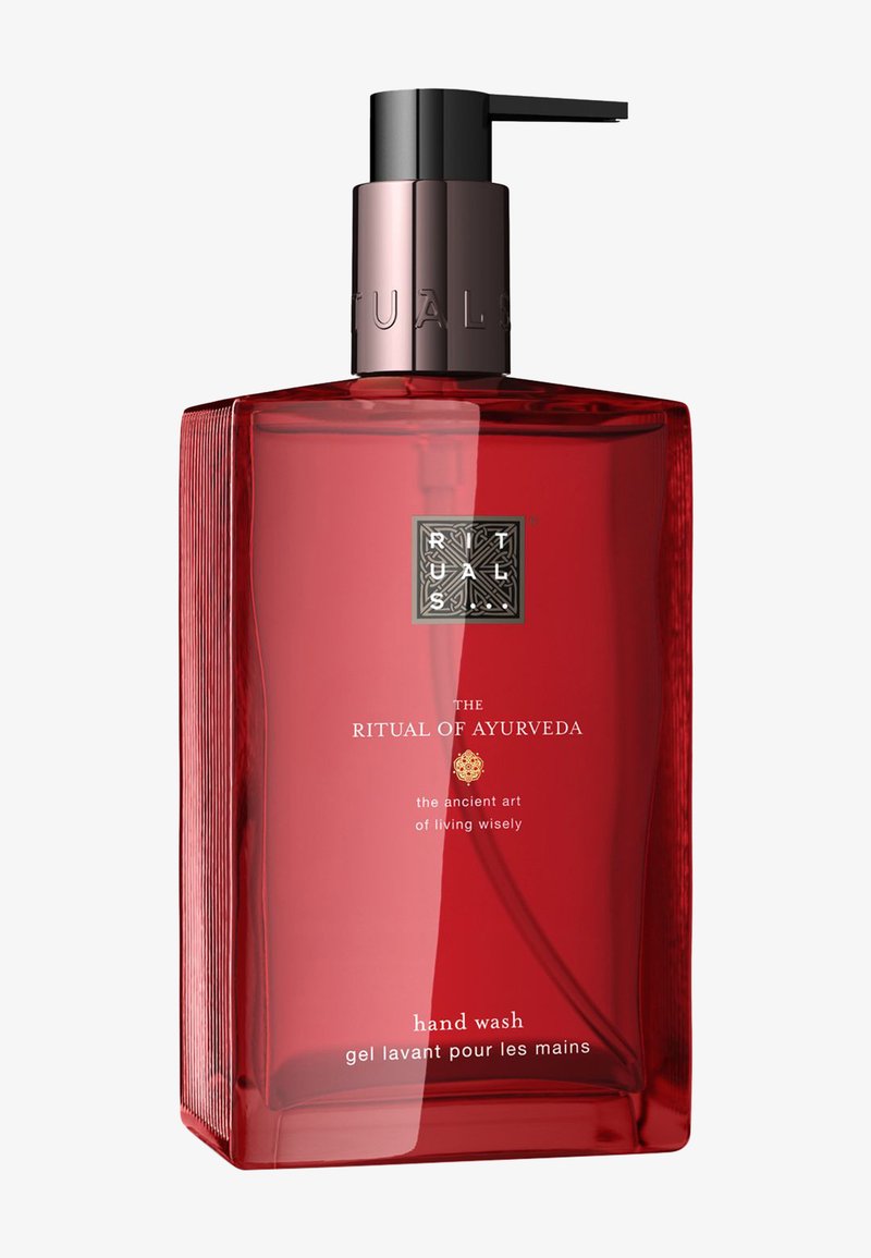 Bouteille rectangulaire rouge avec un bouchon de pompe noir. L'étiquette présente un texte doré indiquant "Le Rituel de l'Ayurveda" et "gel nettoyant pour les mains". Côtés texturés.