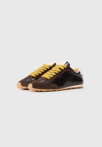 Brązowe i czarne sneakersy z cholewką z zamszu i lakierowanej skóry. Grube żółte sznurówki, teksturowane akcenty i lekka gumowa podeszwa.