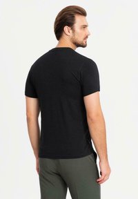 Černé tričko s krátkým rukávem v klasickém střihu, vyrobené z bavlny, s kulatým výstřihem a jednoduchým designem, zobrazené ze zadní strany.