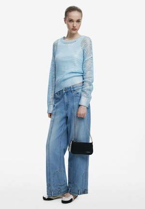 Light blue, mesh-knit sweater with long sleeves; oversized denim pants with large pockets; black shoulder bag; two-tone flat shoes.