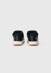 Svarta sneakers med en slät läderöverdel, vadderad krage, vit mellansula och yttersula i gummirubber. Utrustad med dragflikar vid hälarna.