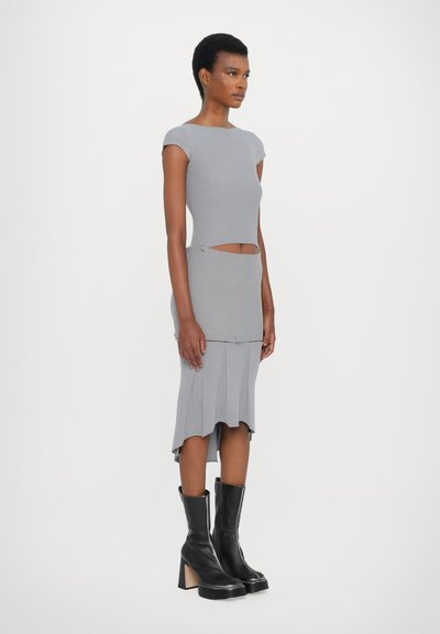 Vestido de punto gris de canalé con detalles recortados, corsé ajustado, dobladillo acampanado y mangas cortas, combinado con botas negras de tacón alto hasta la rodilla.