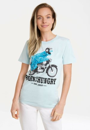 Light blue t-shirt featuring a colorful graphic of a furry character on a motorcycle, with black text reading "BORN TO BE HUNGRY."