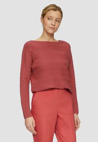 Langärmliger Pullover mit Wellenmuster in einem sanften Rosaton, aus strukturiertem Strickstoff; kombiniert mit passender, maßgeschneiderter Hose.