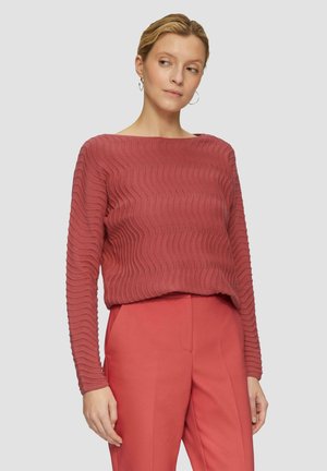 Pull à manches longues avec un motif de vagues dans une couleur rose pâle, fabriqué en tissu tricoté texturé ; associé à un pantalon ajusté assorti.