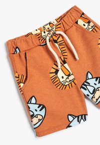 Shorts en coton orange avec des imprimés de lion et de tigre, dotés d'une taille élastique et d'un cordon de serrage, de deux poches latérales et d'une texture douce.