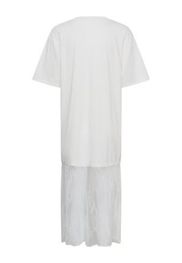 Robe blanche à manches courtes avec un haut uni et une jupe en dentelle transparente longueur genoux, dépassant sous l'ourlet à l'arrière.