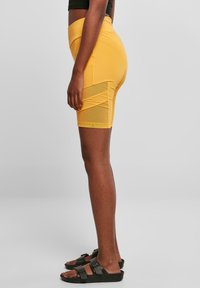 Hoge taille gele shorts van rekbaar materiaal, met meshpanelen aan de zijkanten en een gladde, aansluitende pasvorm.