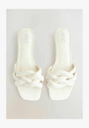 Sandale albe din material țesut, cu vârf pătrat și curele încrucișate. Fabricate dintr-un material texturat și concepute pentru confort.