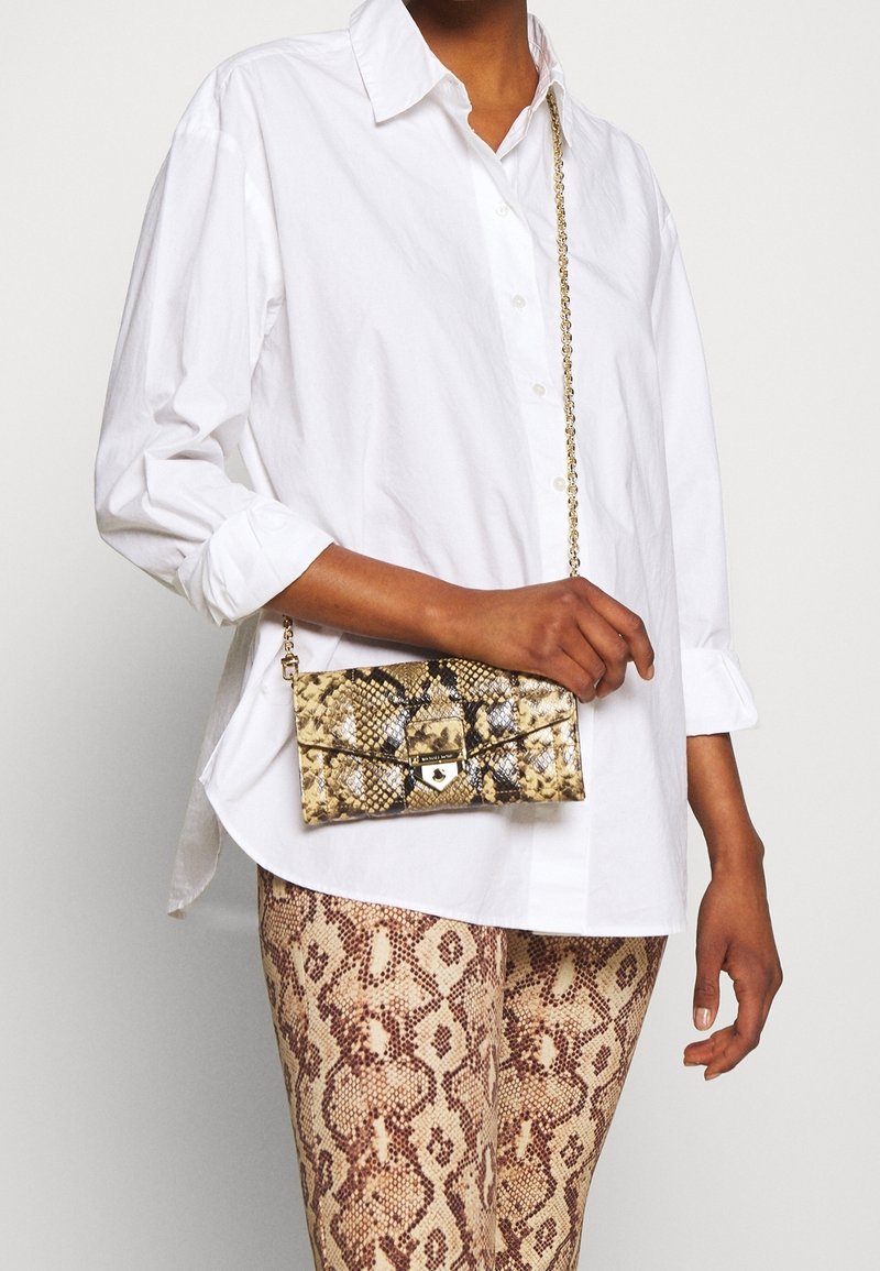 Slangeprint crossbody taske med en guldkæde-strop, der har en tekstureret overflade og et låseelement i nuancer af beige og brun.