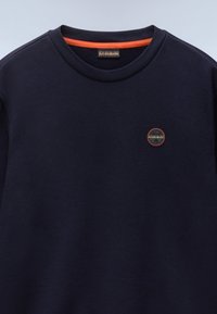 Sudadera de color marino con cuello redondo, acento naranja en el cuello y un pequeño logo circular en el pecho. Tejido suave y texturizado.