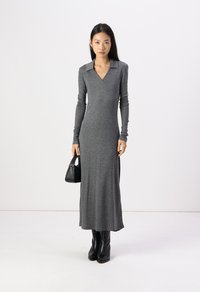 Gray long-sleeve dress with a collar, fitted design, and a floor-length cut. Paired with knee-high black boots and a small black handbag.