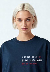 T-shirt oversize en coton bleu marine avec un col rond. Présente un imprimé texte blanc et rouge sur le devant. Texture du tissu douce.