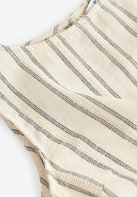 Tissu en lin naturé avec de fines lignes noires sur un fond crème, présentant un tissage texturé et un design léger et respirant.