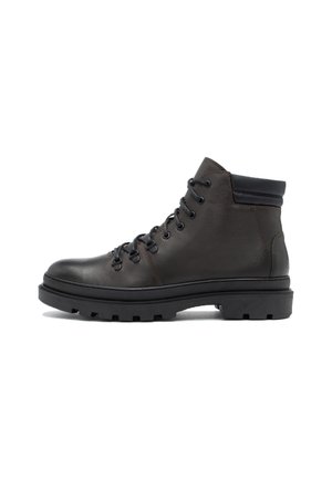 Botas de tobillo de cuero marrón oscuro con una superficie texturizada, detalles en negro, cierre de cordones en la parte delantera y suela robusta con profundas ranuras para mayor tracción.
