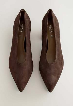 Braune Wildleder-Pumps mit spitzem Zeh und breitem Ausschnitt an den Seiten. Glatte Textur, minimalistisches Design und ohne sichtbare Beschläge.