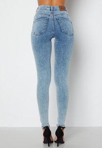 Hög midja, ljusblå skinny jeans i denim med en blekt finish, fem fickor och bälteshällor, kombinerat med svarta högklackade skor.