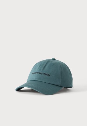 Casquette de baseball bleu sarcelle avec visière incurvée et texte noir brodé "contemporary dandy" sur le panneau avant, présentée sur fond blanc.