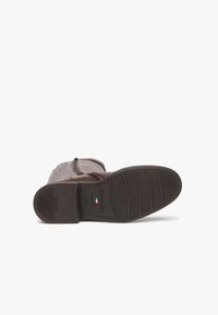 Scarpa di pelle marrone scuro con tomaia liscia, dettagli testurizzati e suola in gomma con modelli di battistrada orizzontali.