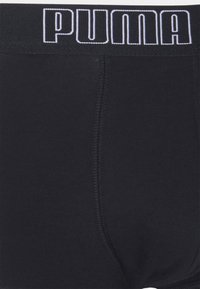 Schwarze Baumwollslips mit einem breiten elastischen Bund, der mit weißen "PUMA"-Markierungen versehen ist. Glatte Textur mit flachen Nähten und klassischer Silhouette.
