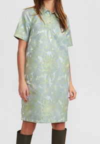 Kortärmad klänning i ljusblått med blommönster i grönt och vitt. Har en knapp-up krage och avkopplad passform. Slät tyg.