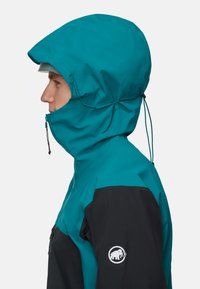 Hooded jacket in teal en zwart stof, met een zichtbare rits, verstelbare trekkoorden en een logo patch op de zwarte mouw.